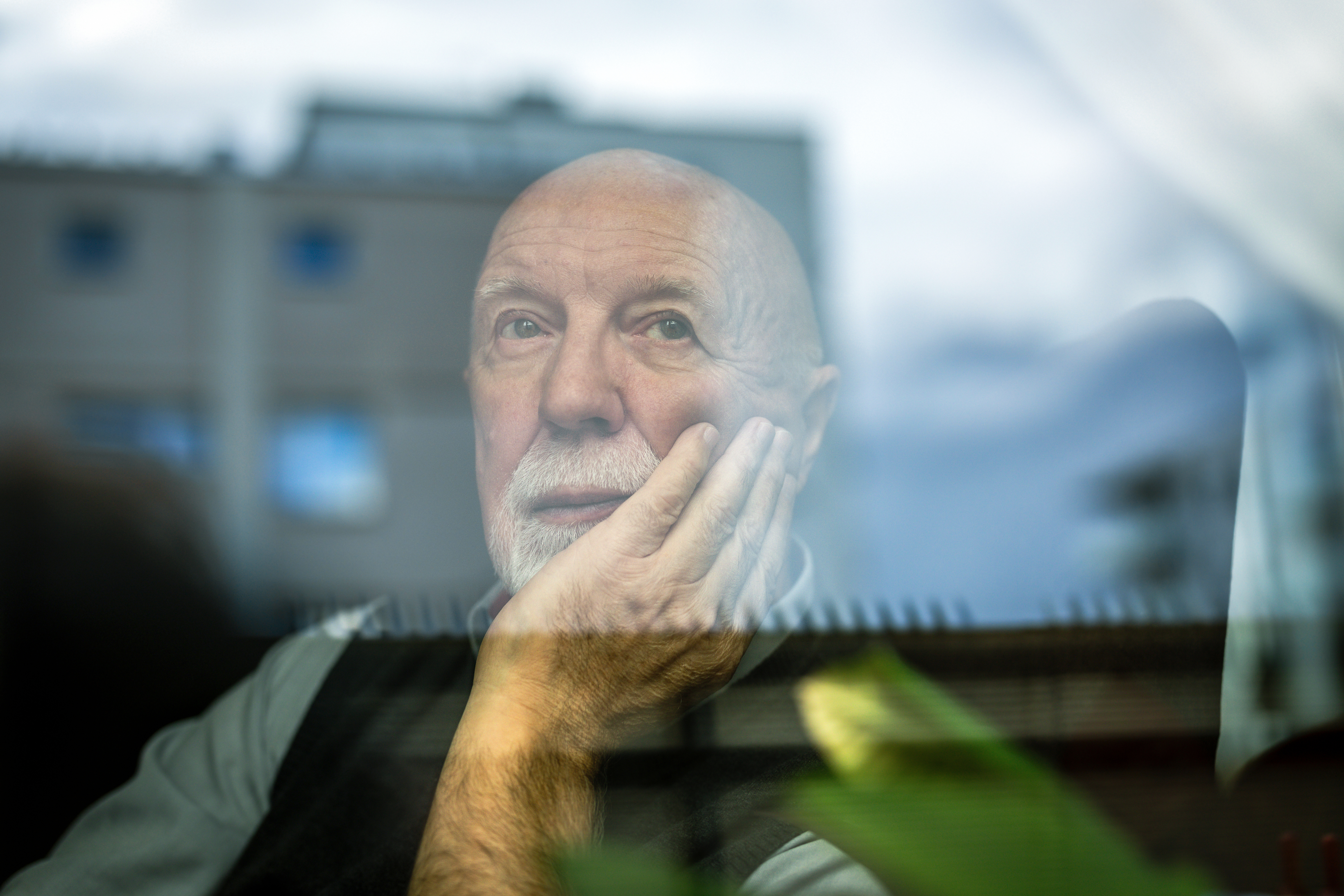 Mann schaut nachdenklich aus dem Fenster